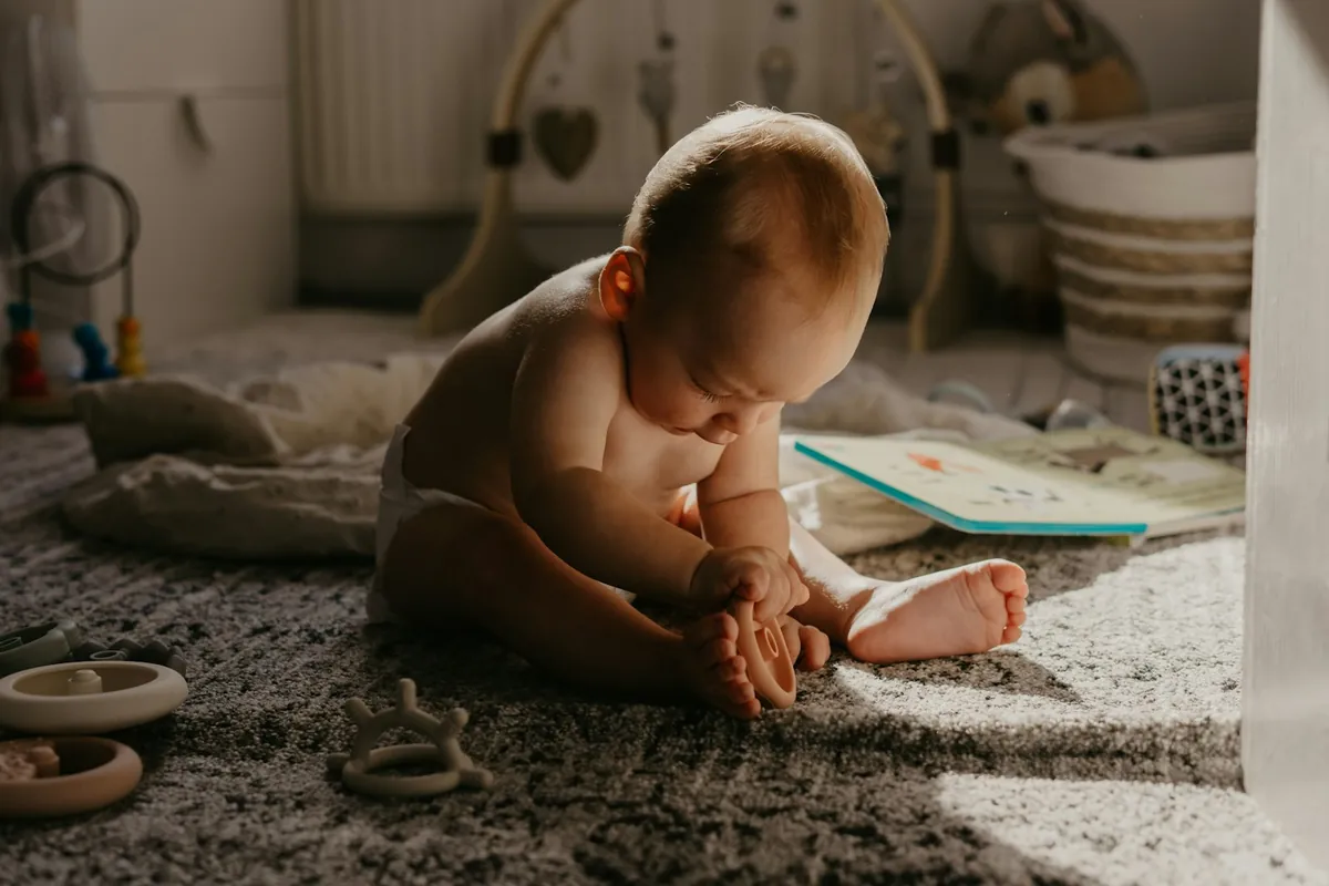 A baby exploring soft toys spread out on a rug