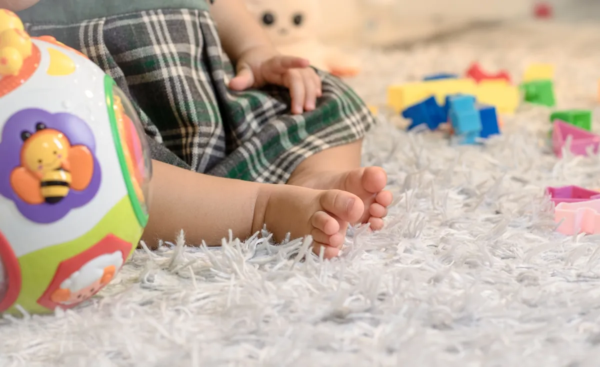 A baby reaching for soft toys while playing on a rug
