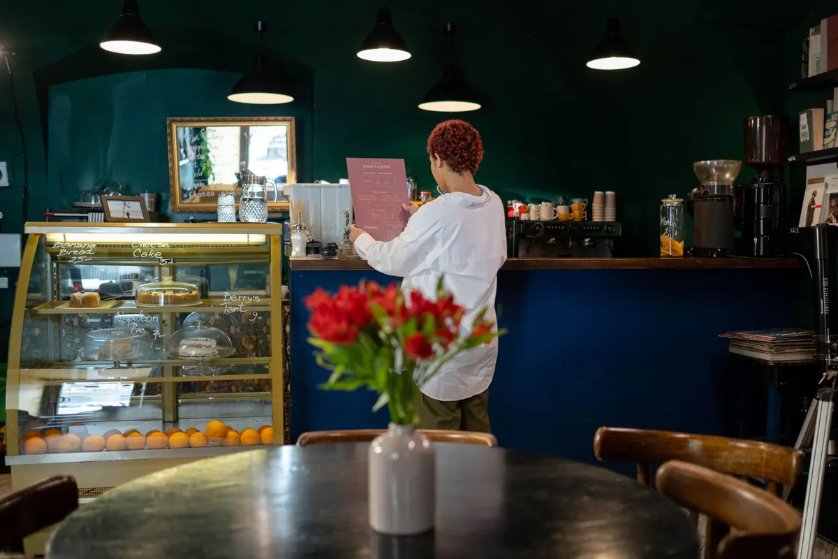 A cafe counter with a pastry display case and flowers