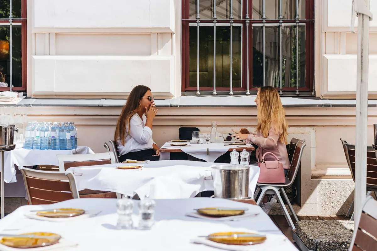 Two people sitting at a laid cafe table outdoors