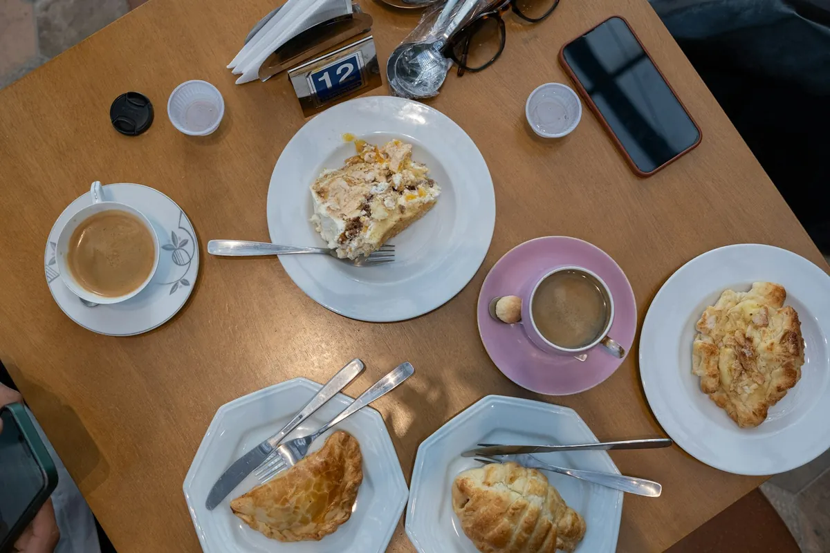 A cafe table laid with coffee cups and pastries for two