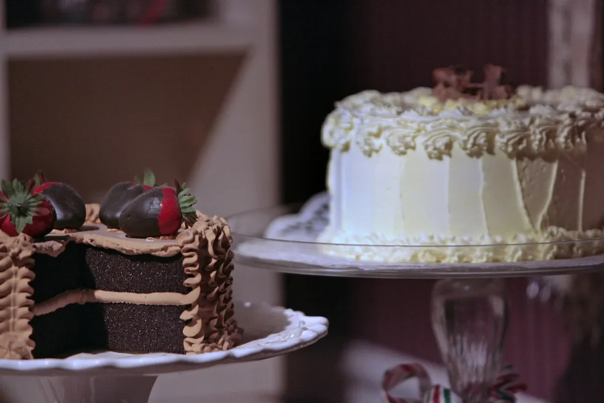 A tiered cake stand beside a cut chocolate cake