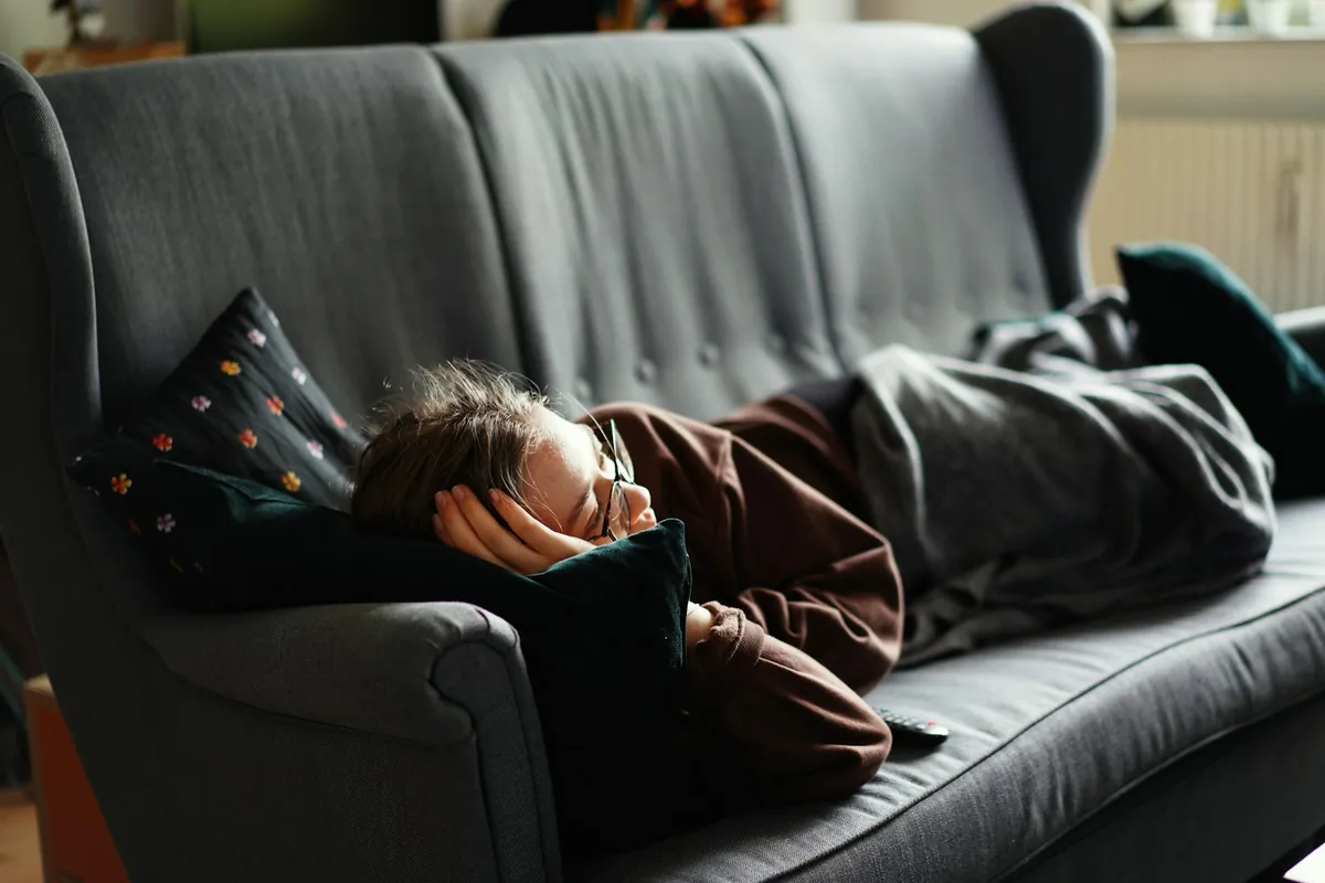 A child lying asleep along a grey sofa