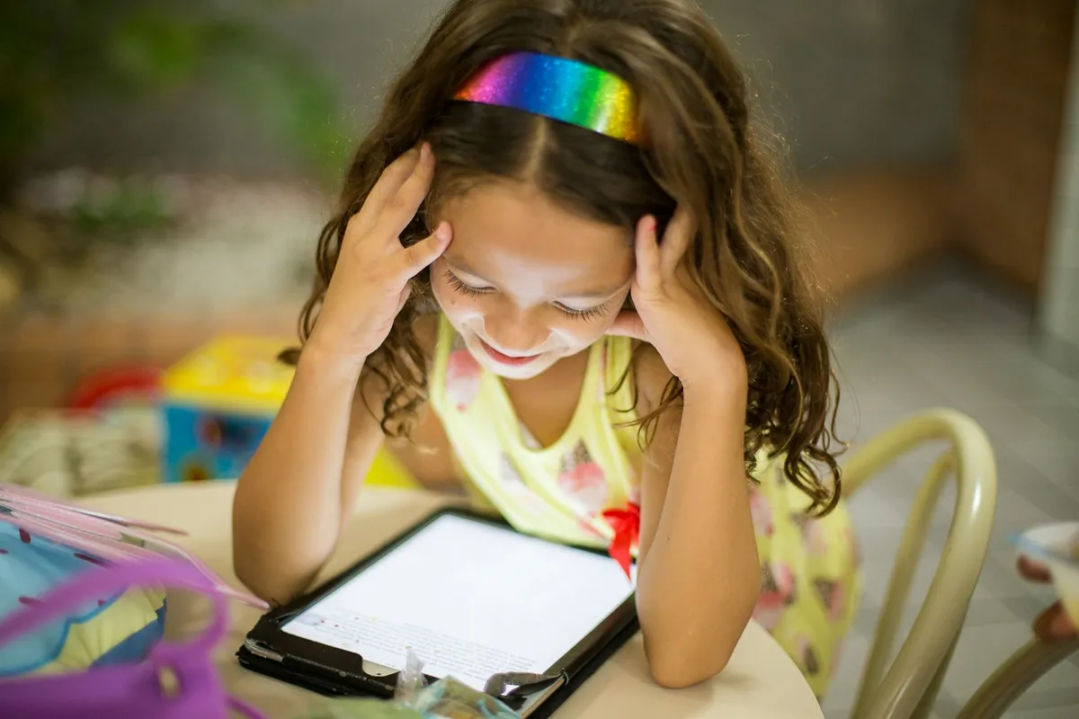 A child resting their head while a tablet sits on the desk
