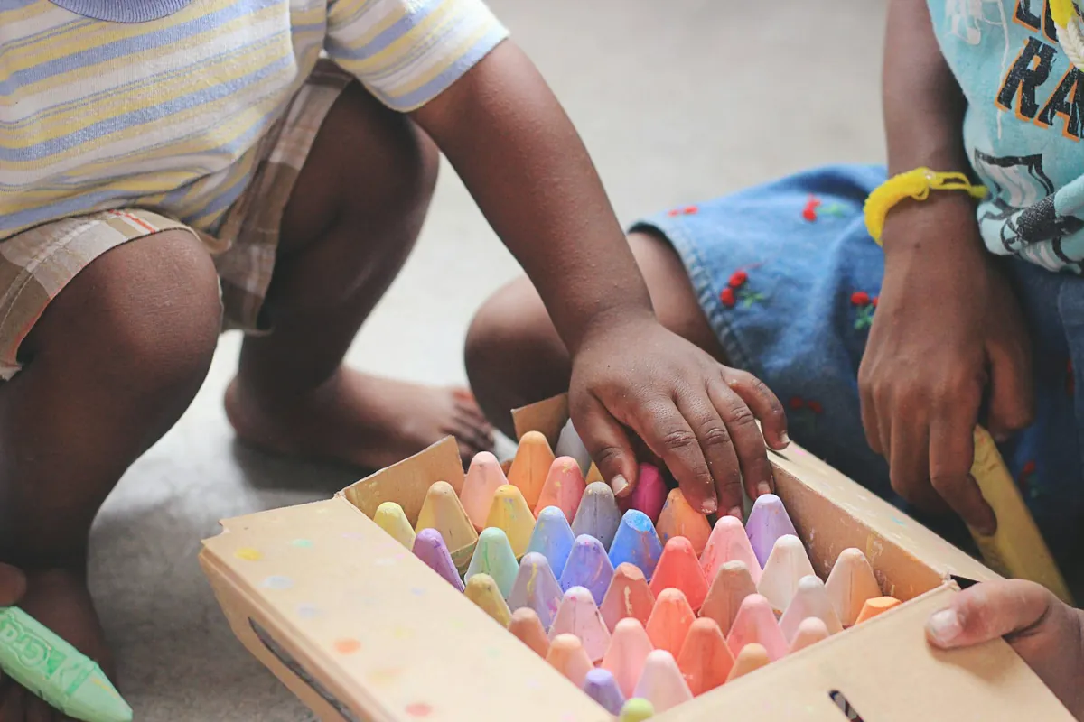 A child choosing from a wooden box of coloured chalks