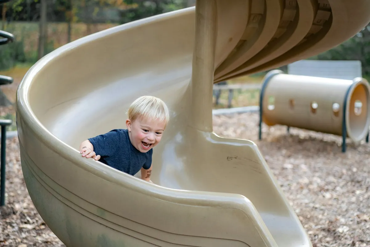 A young child coming down a playground slide