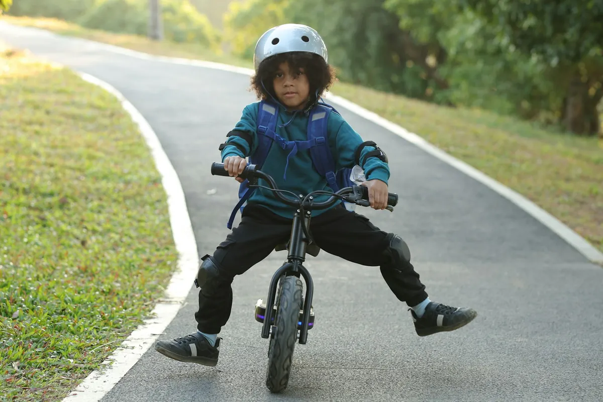 A child cycling along a wide paved path