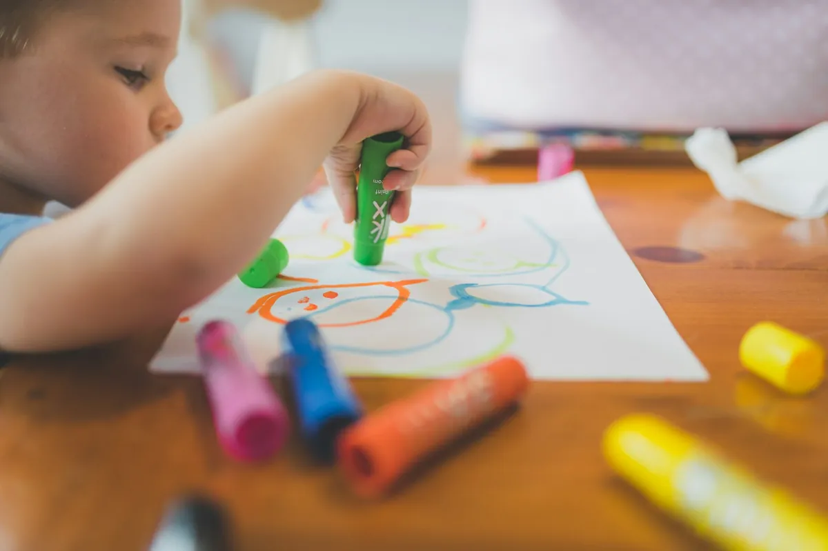 A young child drawing with crayons at a table