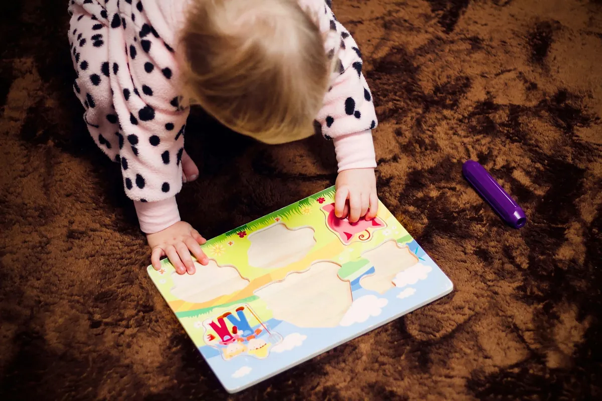 A young child drawing in a colouring book indoors
