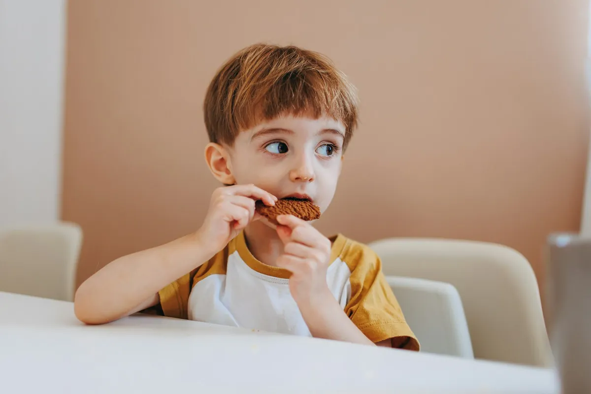 A young child sitting at a table eating a snack