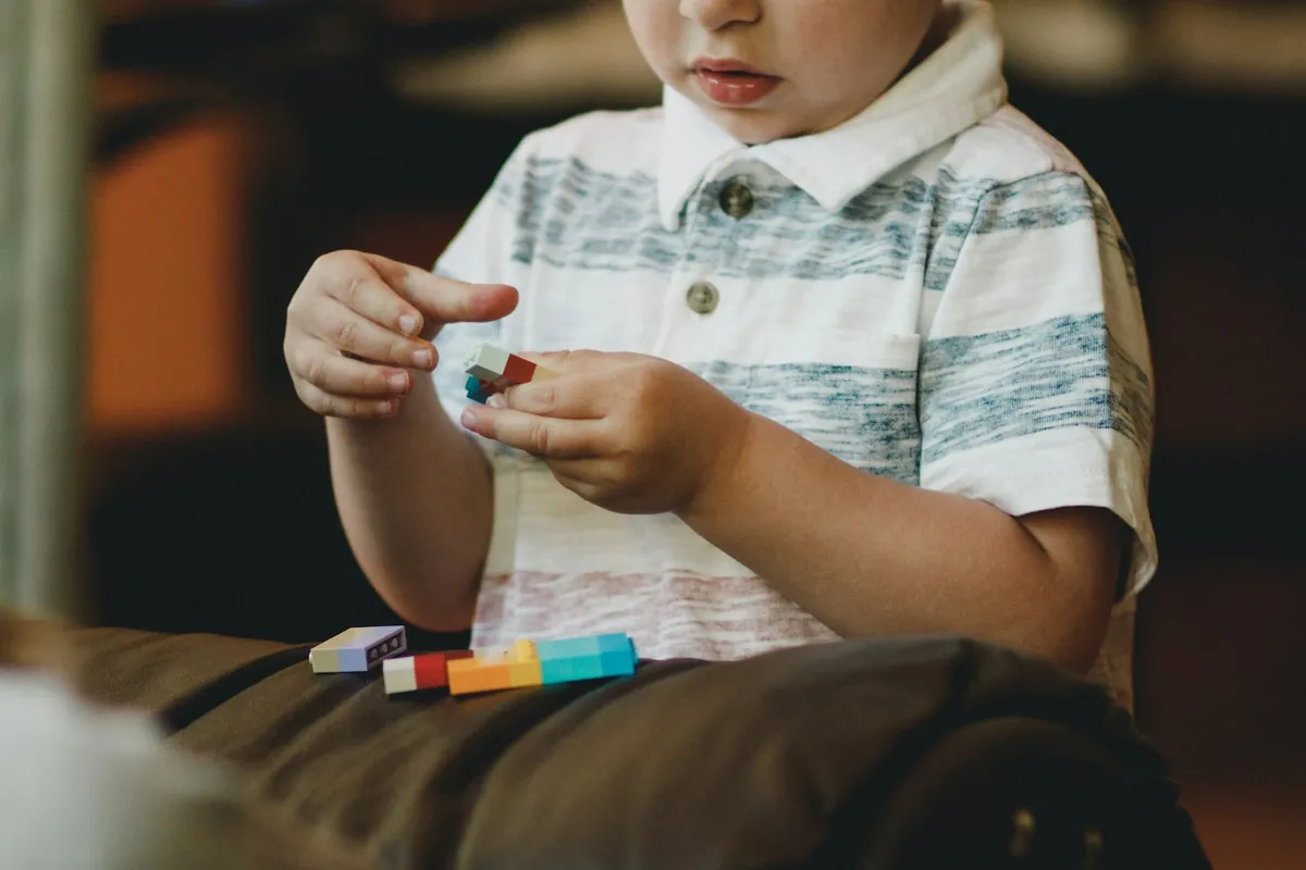A young child fitting coloured building blocks together