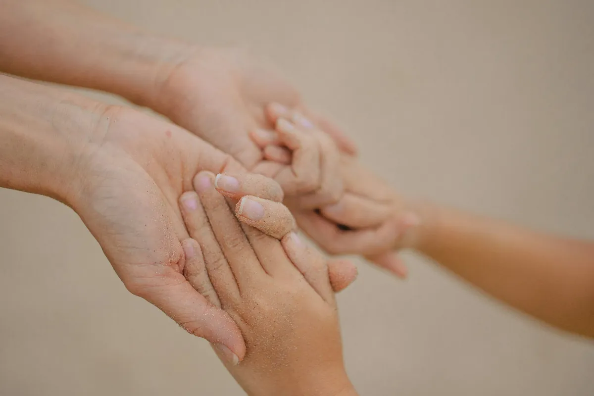 A child hand held gently by an adult hand