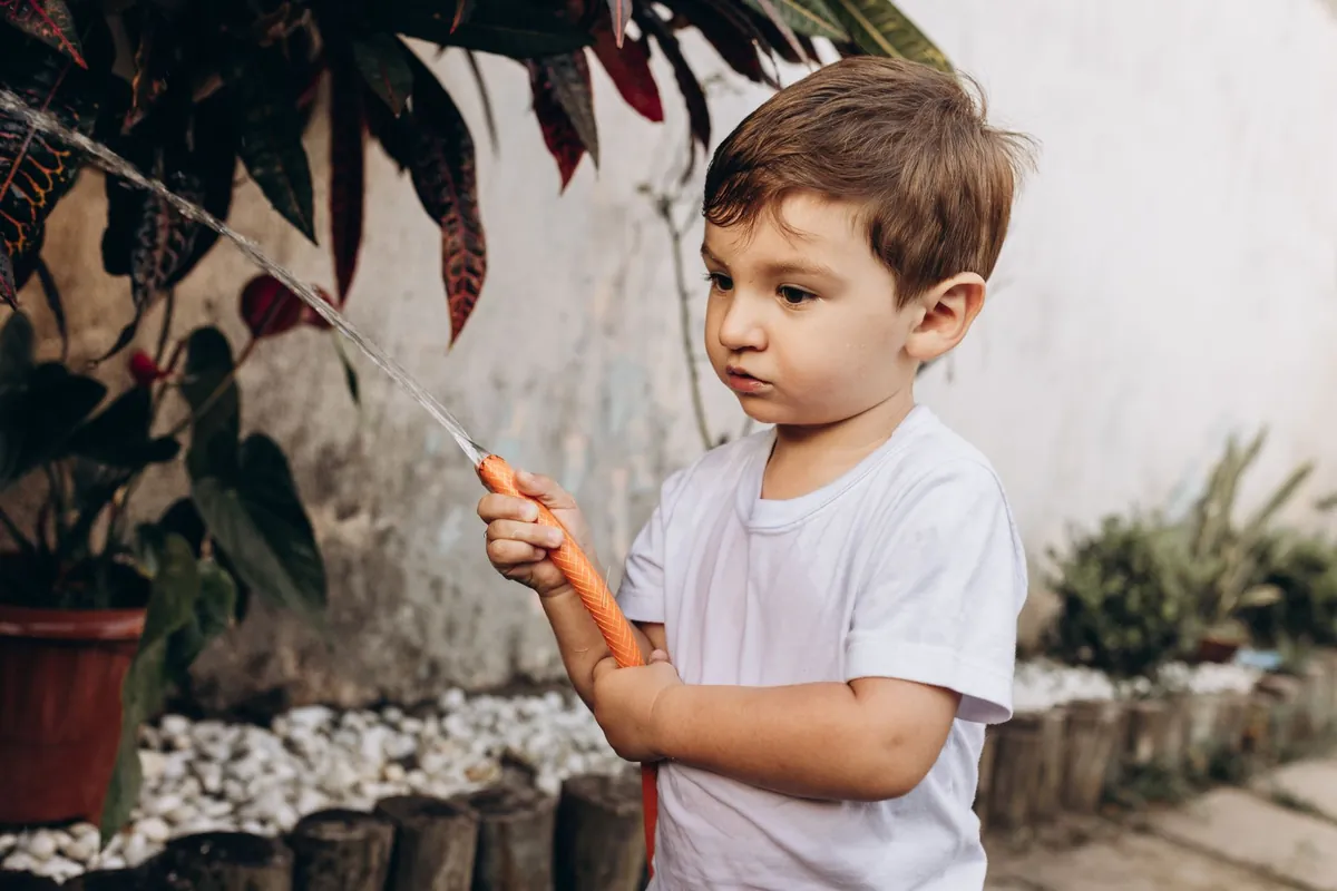 A young child holding a paintbrush outdoors