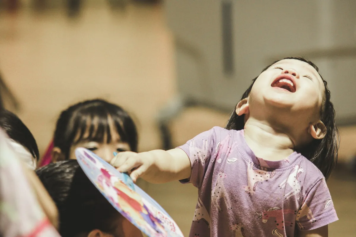 A young child laughing while playing at a party