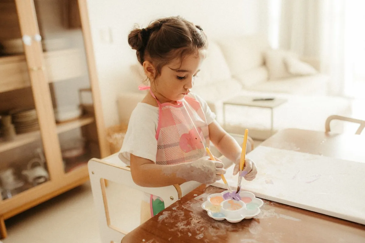 A child painting at a low table in a bright room