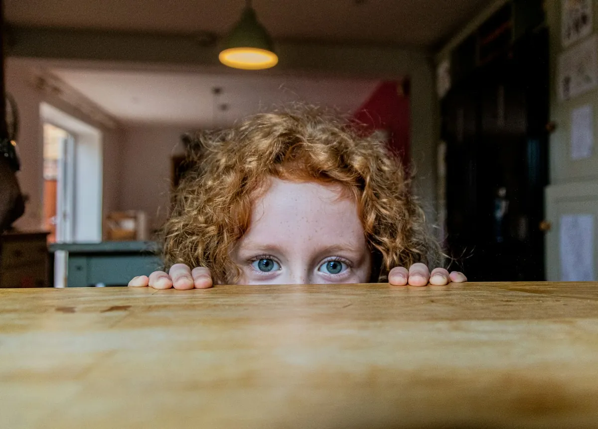 A child peering over the edge of a table
