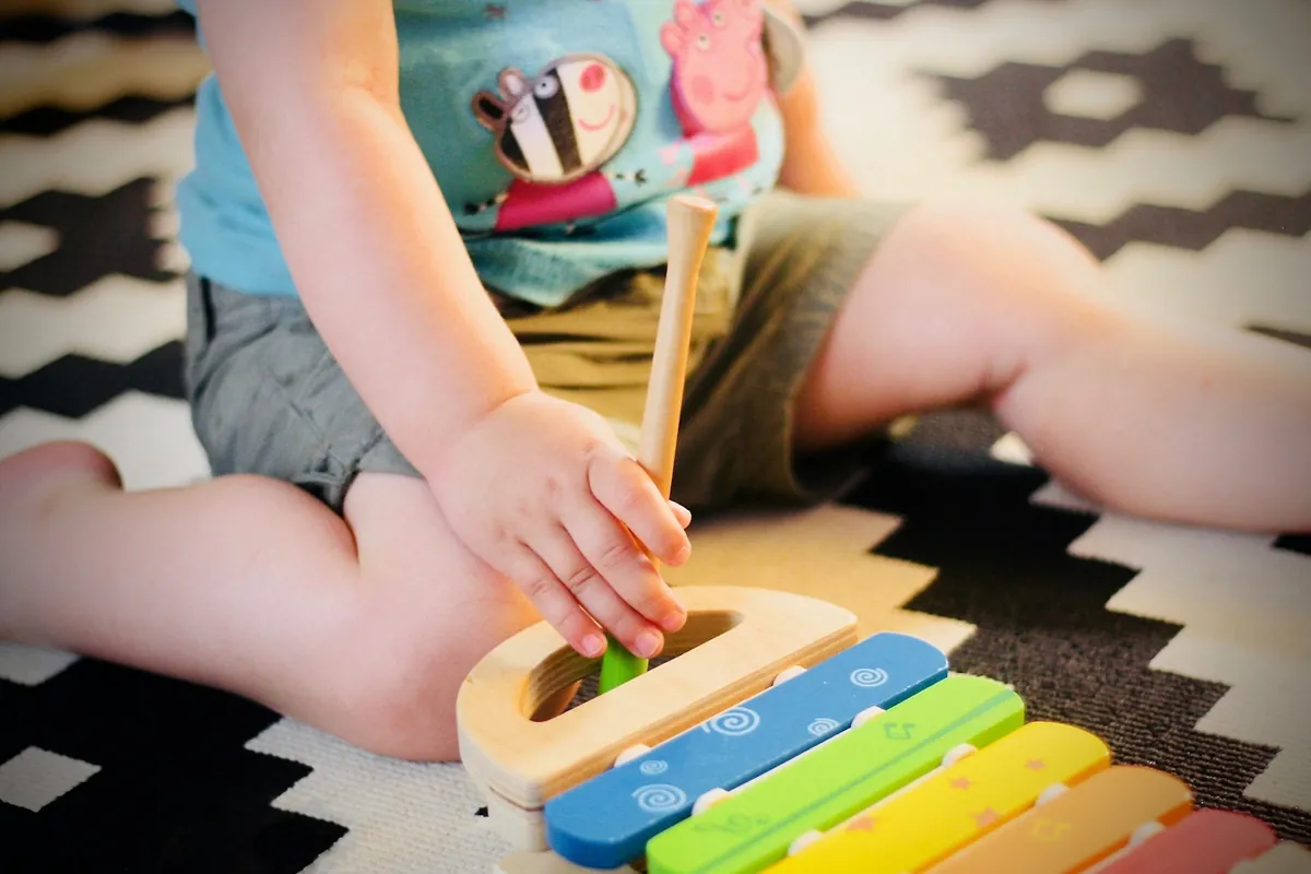 A young child playing a toy instrument on a patterned rug