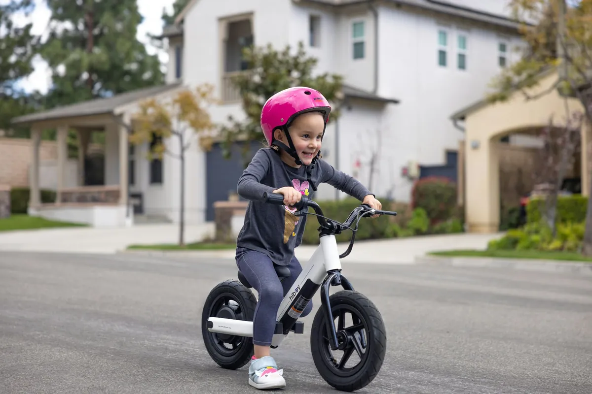 A child in a helmet riding a balance bike on a street