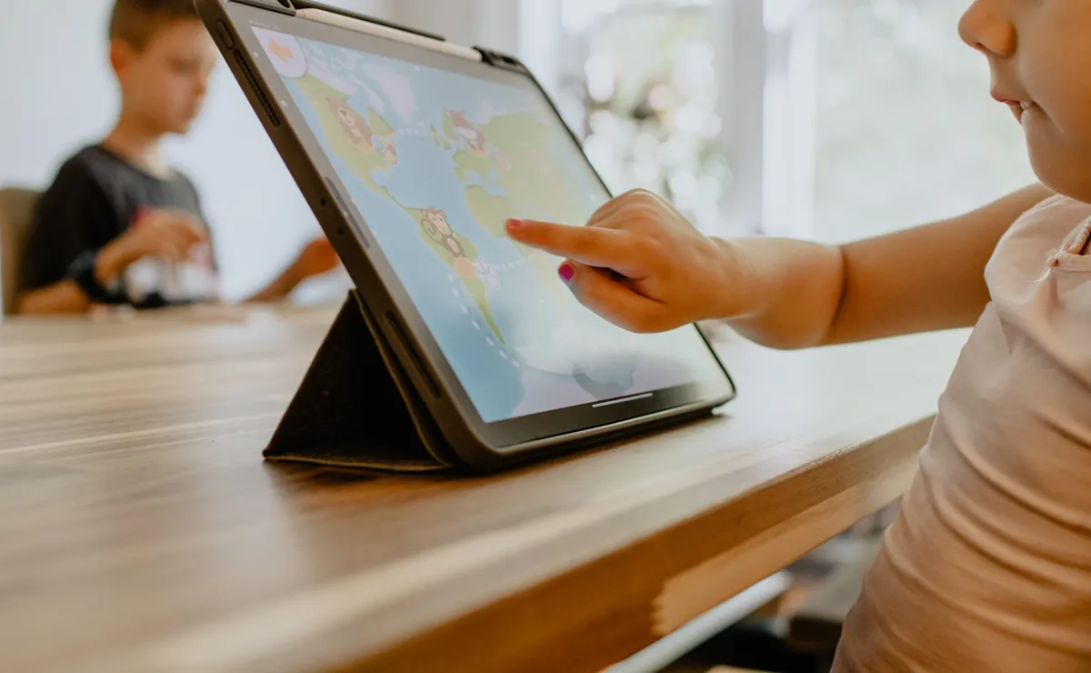 A child reaching towards a tablet propped on a table