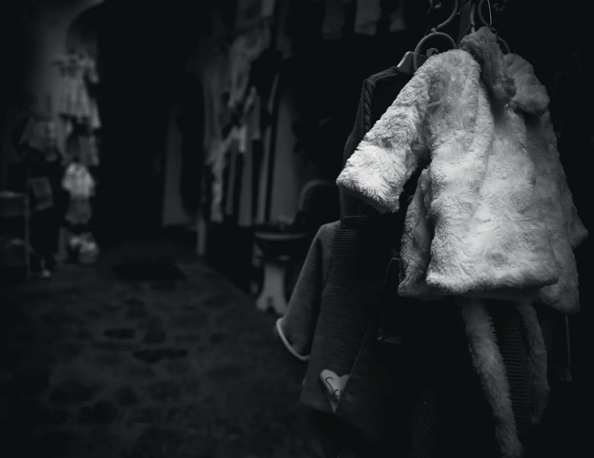A winter coat hanging on a hook in a dim hallway