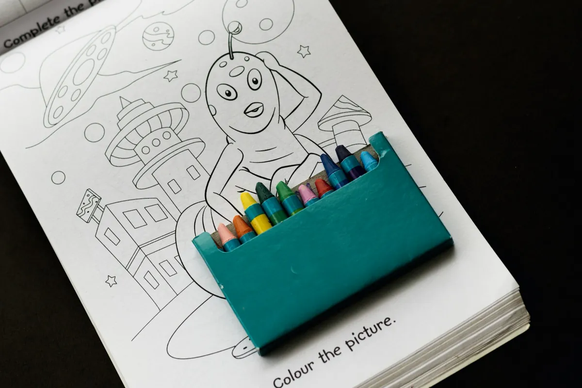 An open colouring book with a pack of crayons on it