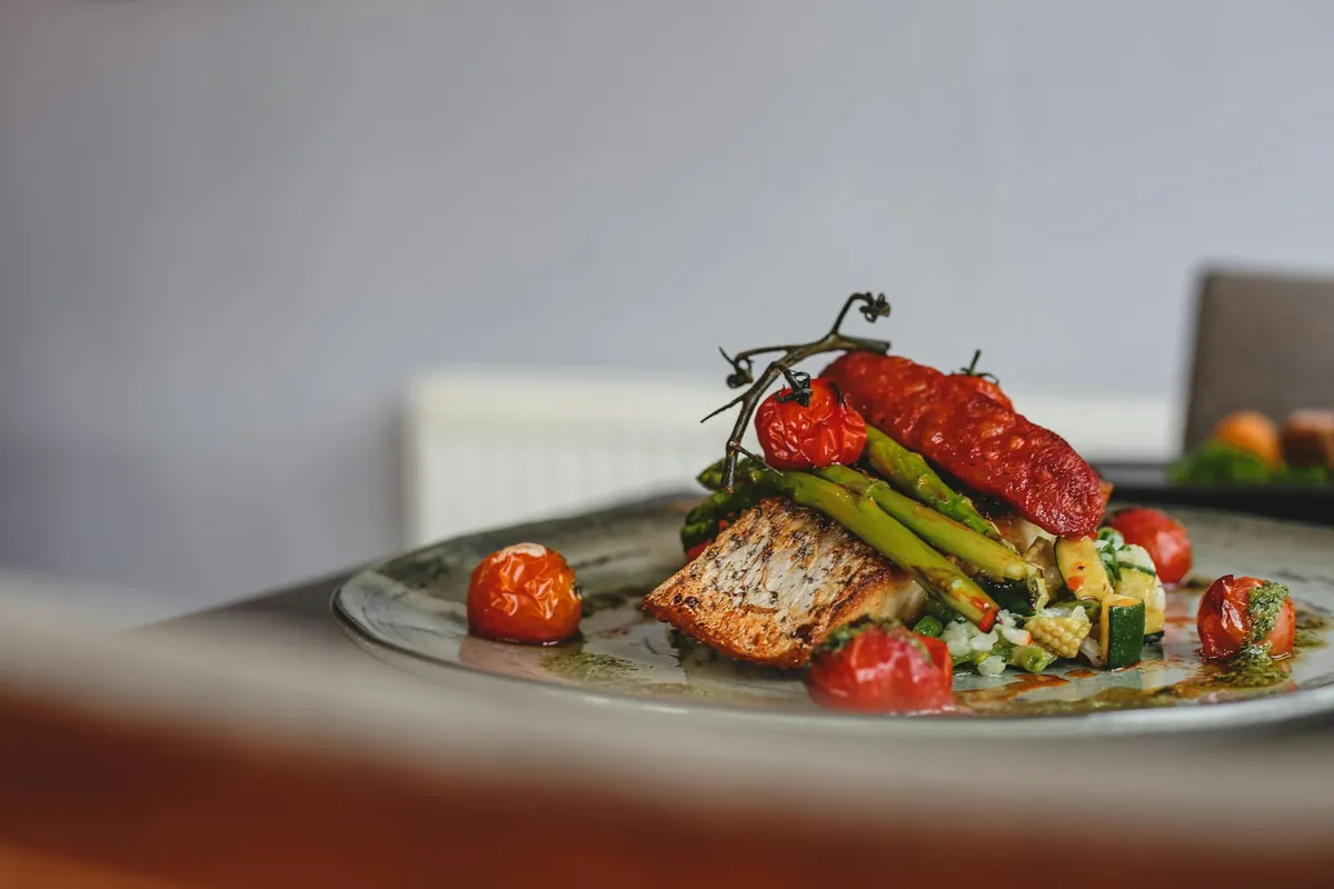 A cooked plate of fish and vegetables at a table