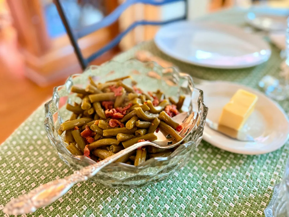 A glass dish of cooked green beans on a table