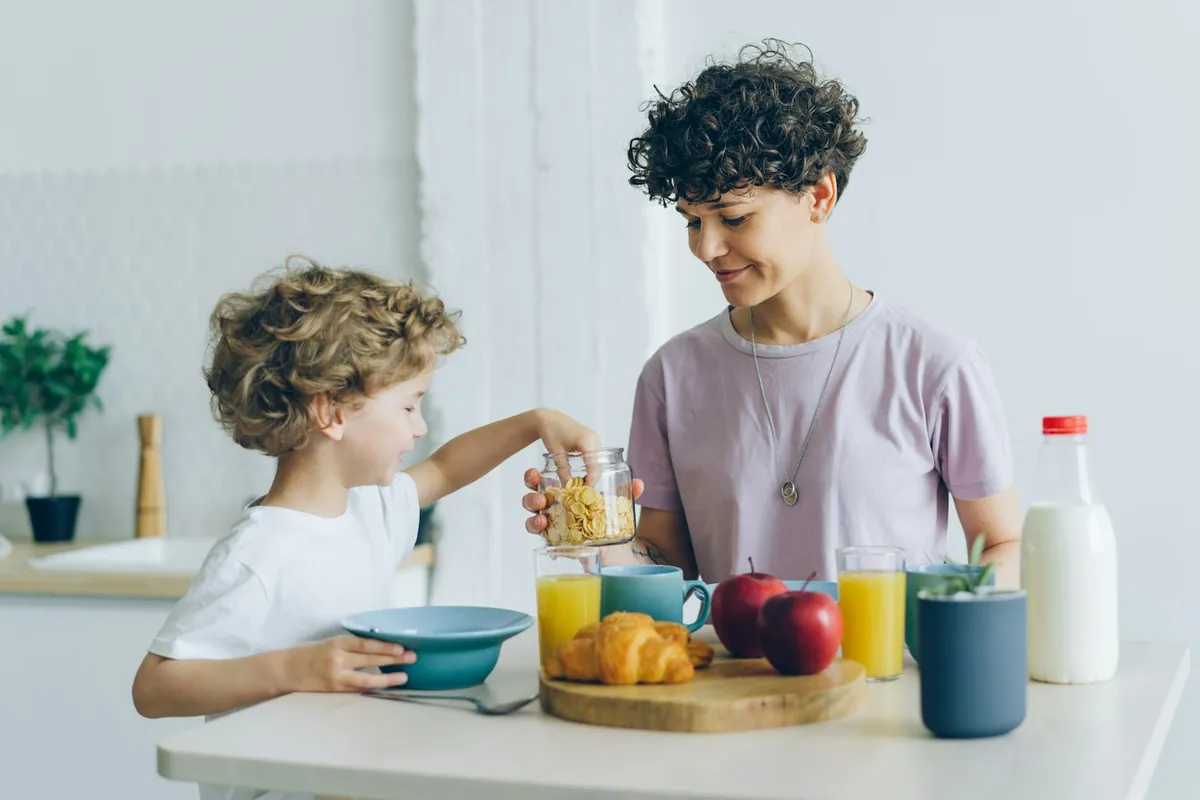 An adult and two children at a breakfast table together