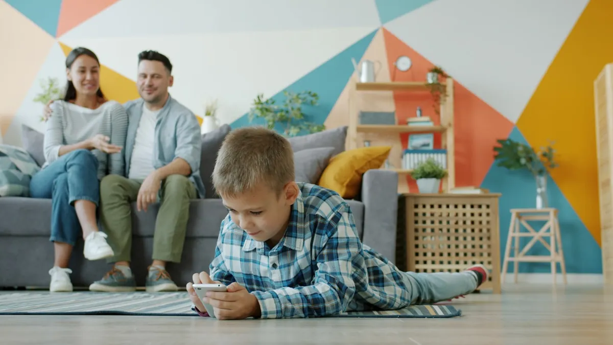 Adults on a sofa while a child plays on the floor