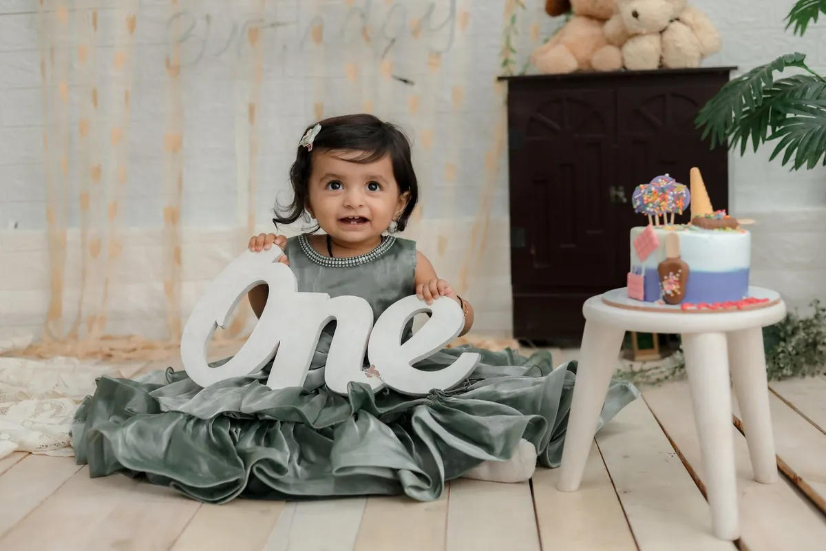 A baby seated beside letters spelling out the word one