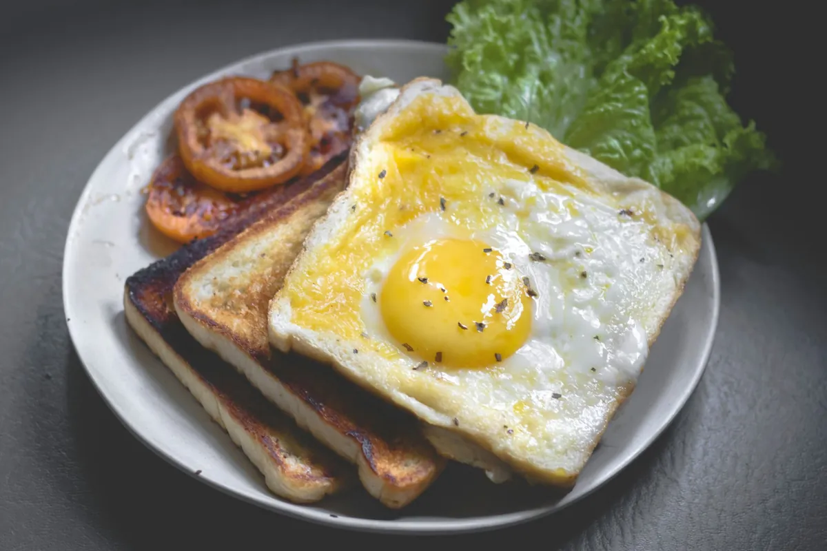 A fried egg served on toast with tomato