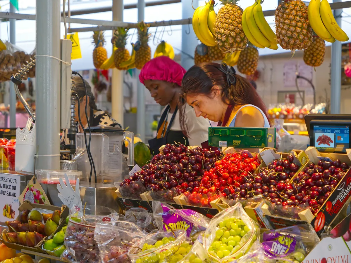 A market fruit stall with cherries and hanging bananas