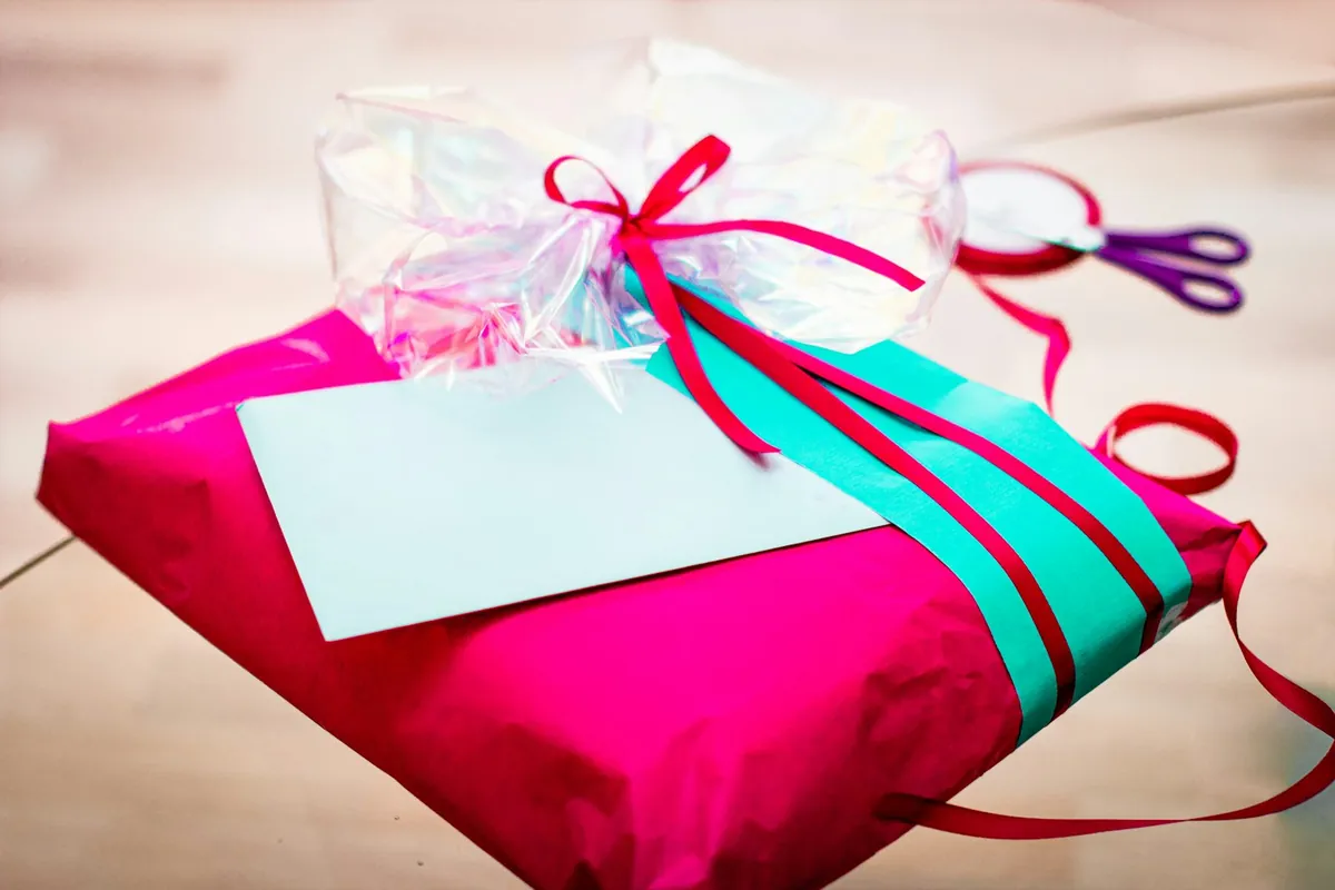 A wrapped gift with curling ribbons and a blank card