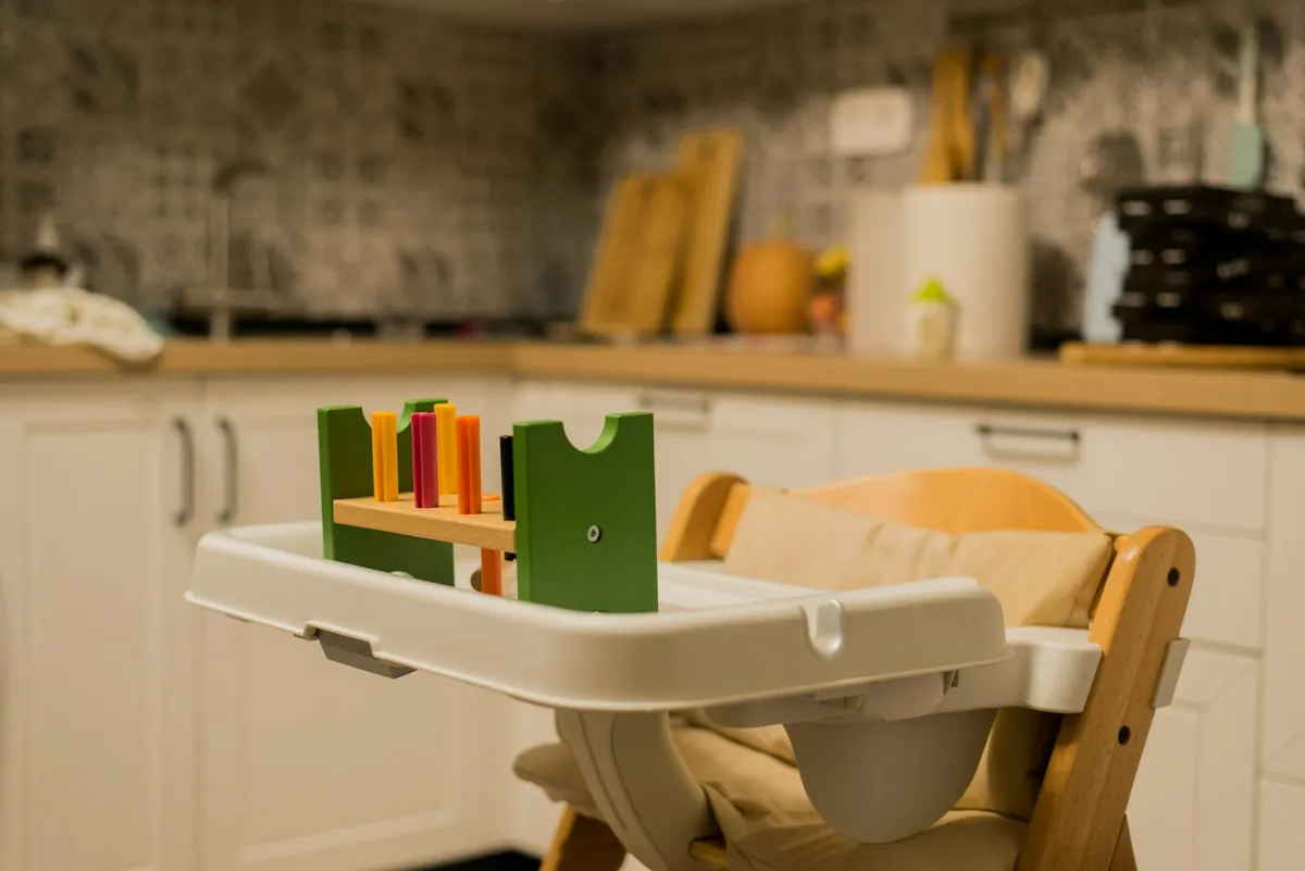 A wooden high chair with a tray in a kitchen