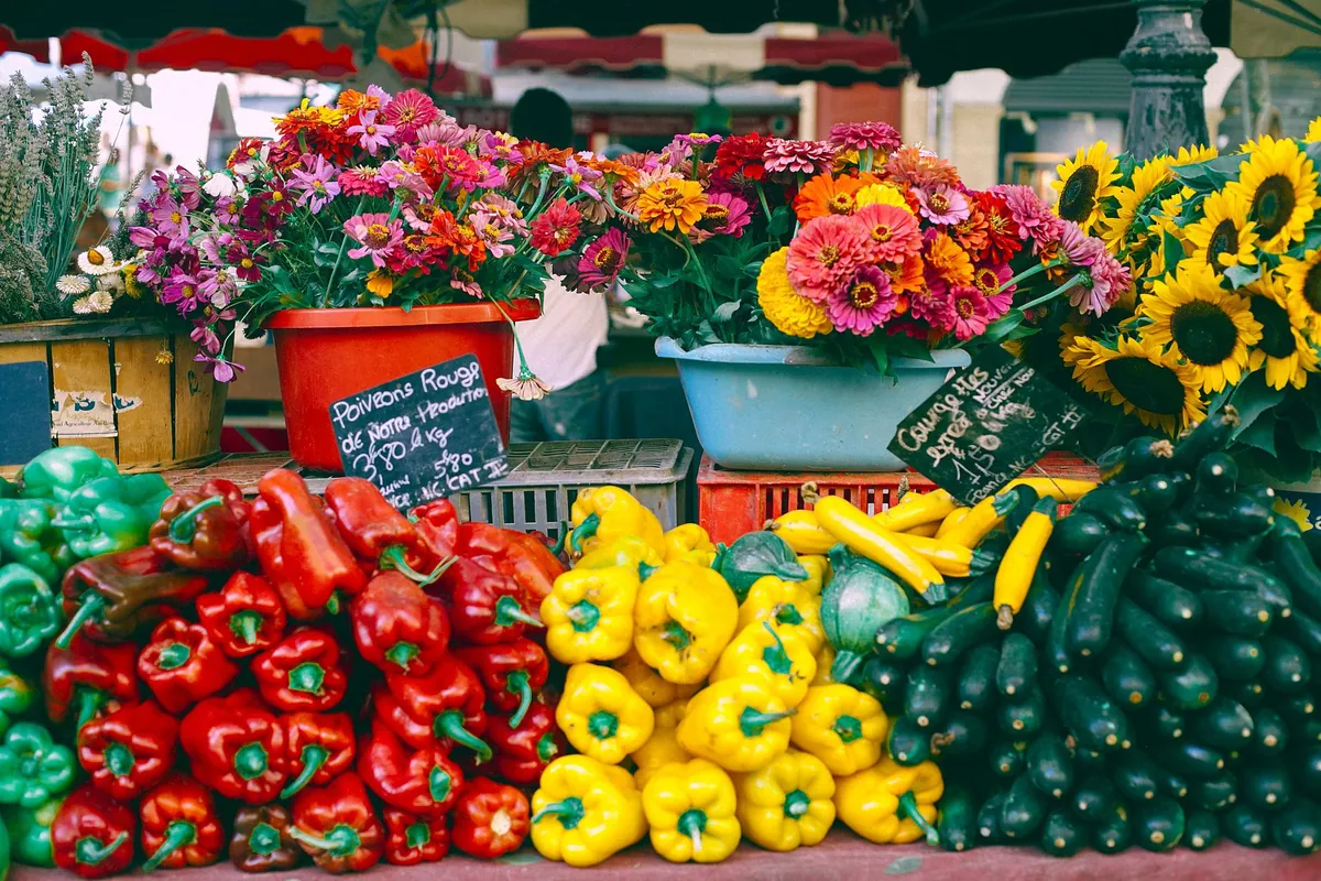 A market stall displaying cut flowers and peppers
