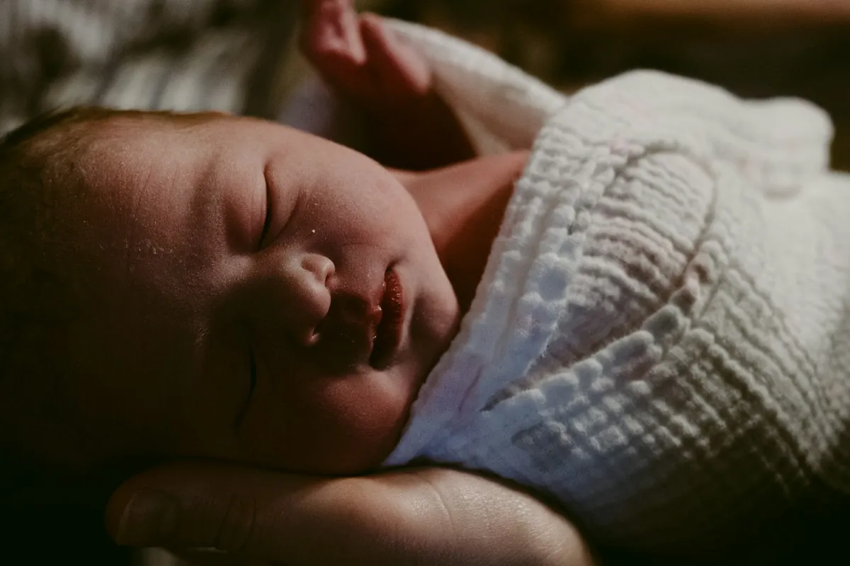 A newborn baby held closely in someone arms