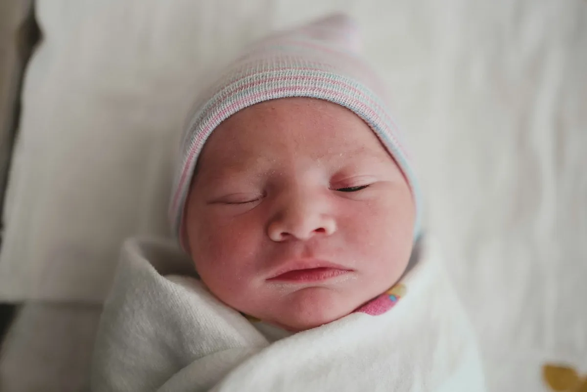 A sleeping newborn wearing a soft knitted hat