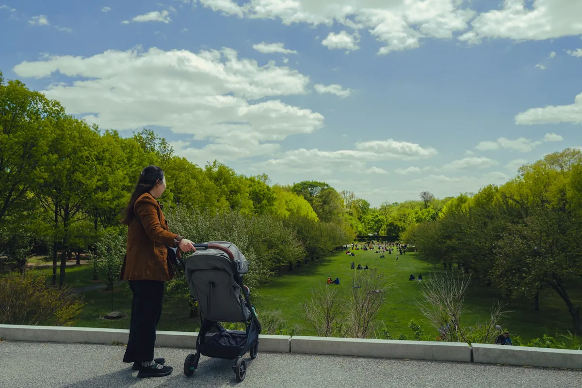 A parent pushing a pram along a path beside water