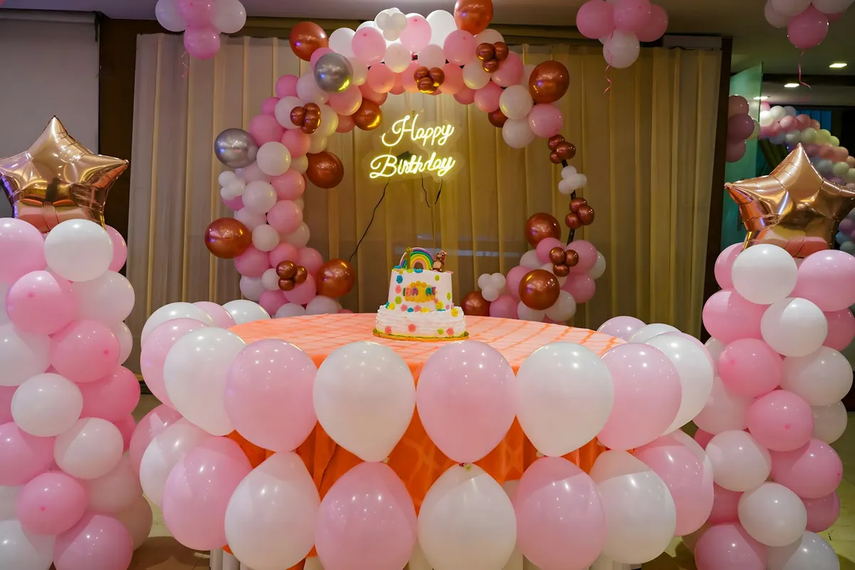 A party table framed by pink and white balloons