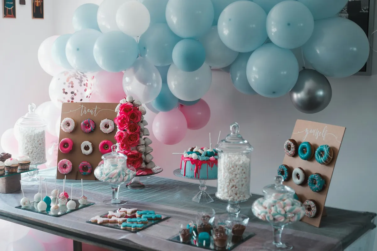 A pastel balloon arch behind a table of party desserts