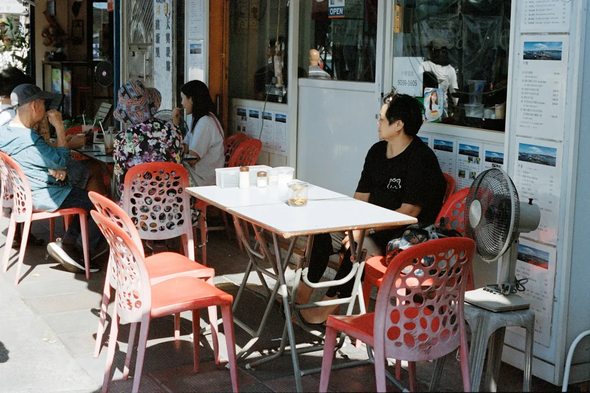 A pavement cafe with red chairs and small tables