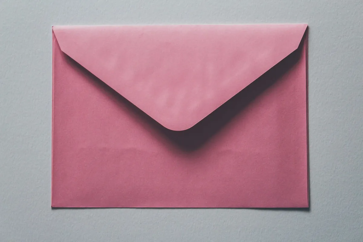 A pink paper envelope on a grey background