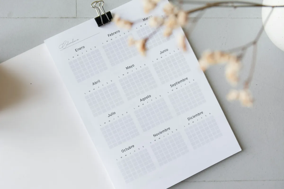 A planner open on a desk beside dried flowers