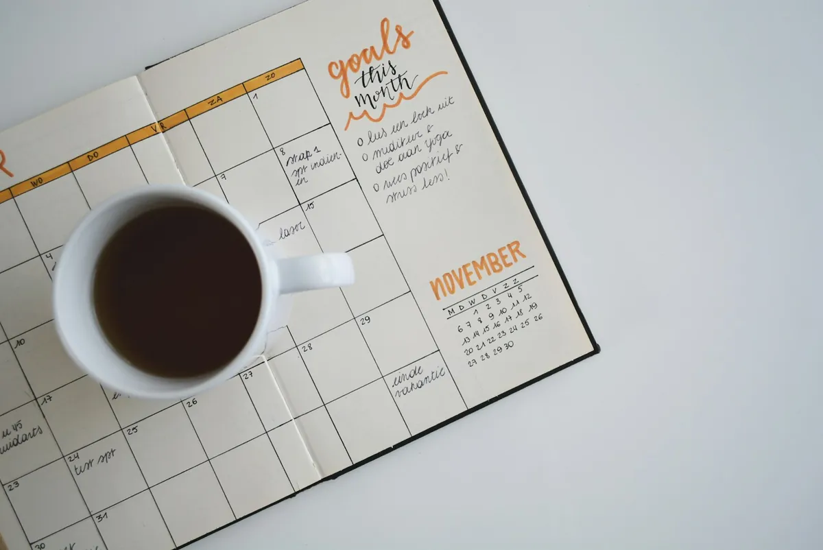 A planning calendar and a cup of coffee on a desk