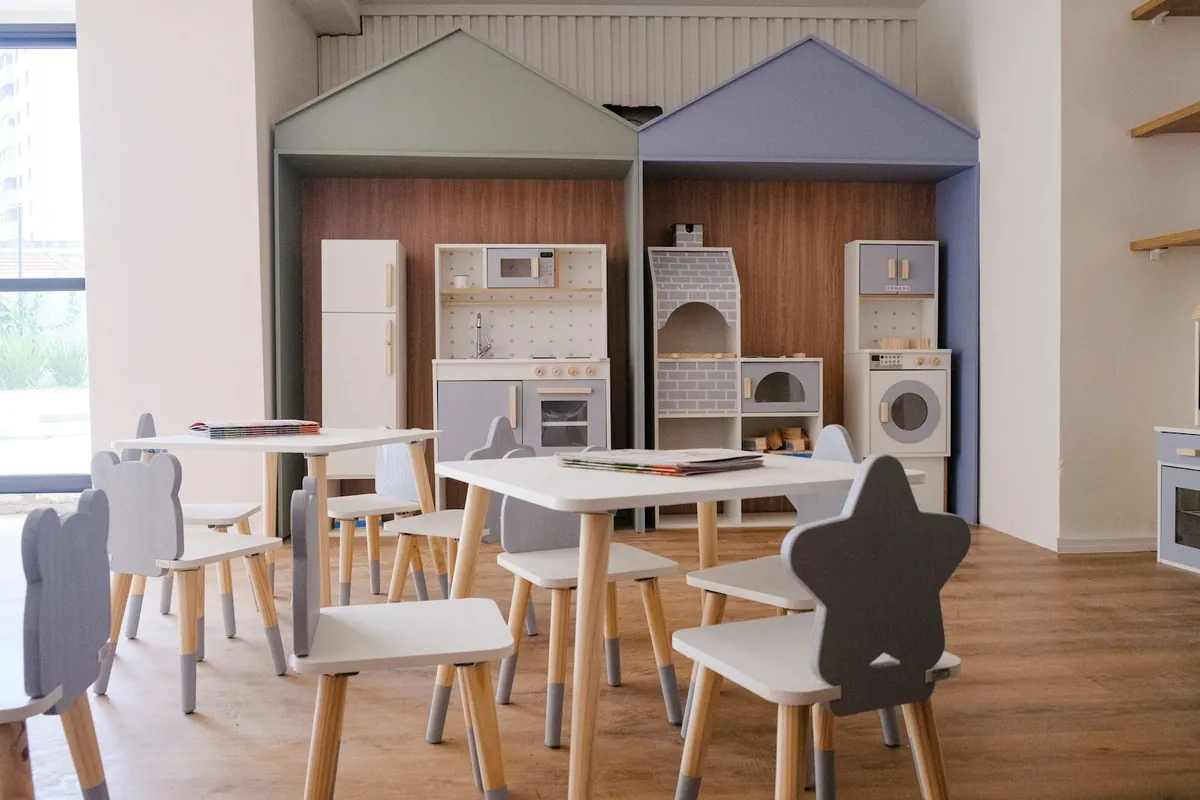 A play room set up with small tables and a toy kitchen