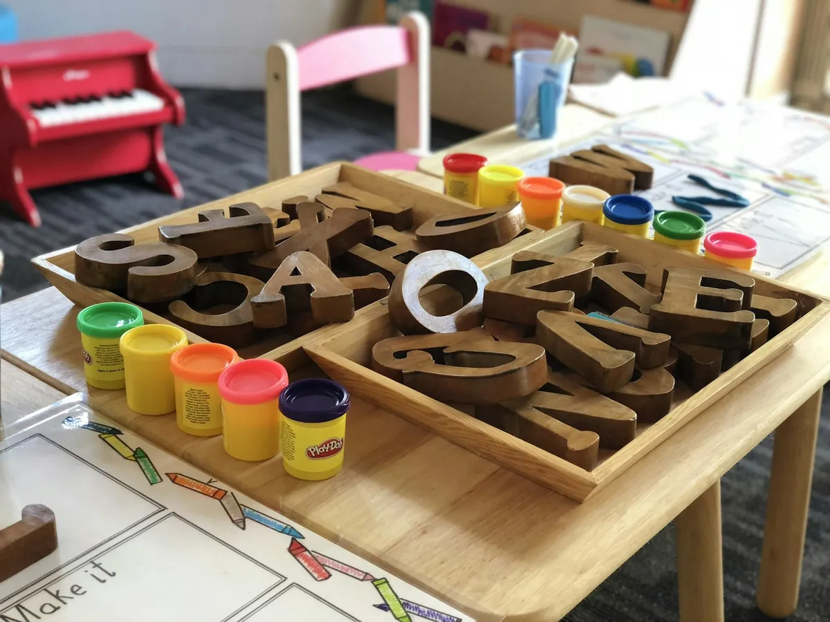 A play table with wooden letters and pots of dough