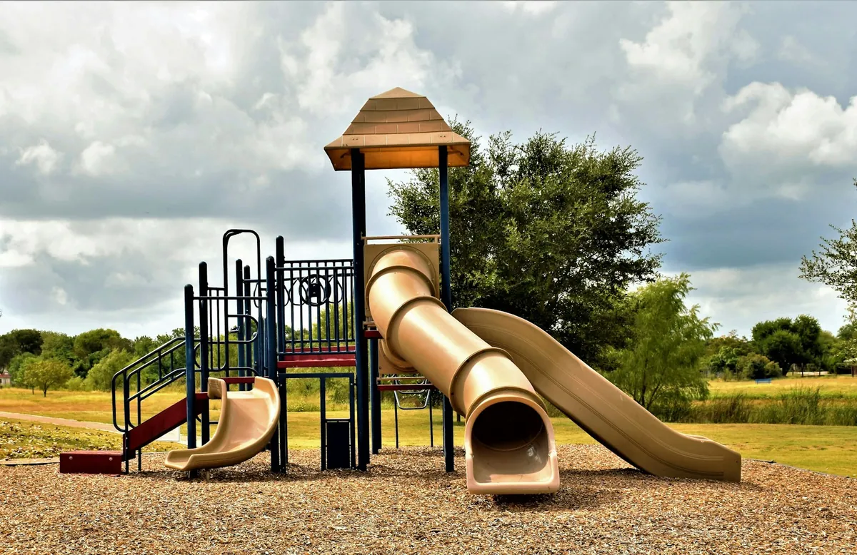 A wooden playground structure with a slide in a park