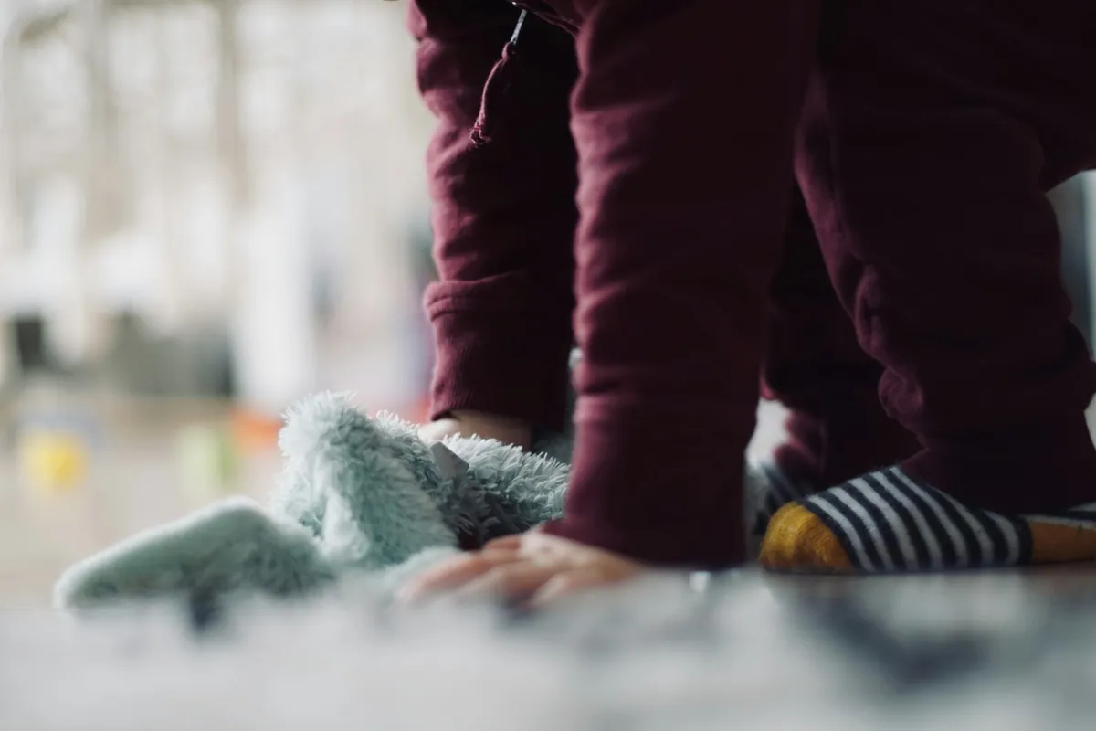 A small child pulling on a sock while seated