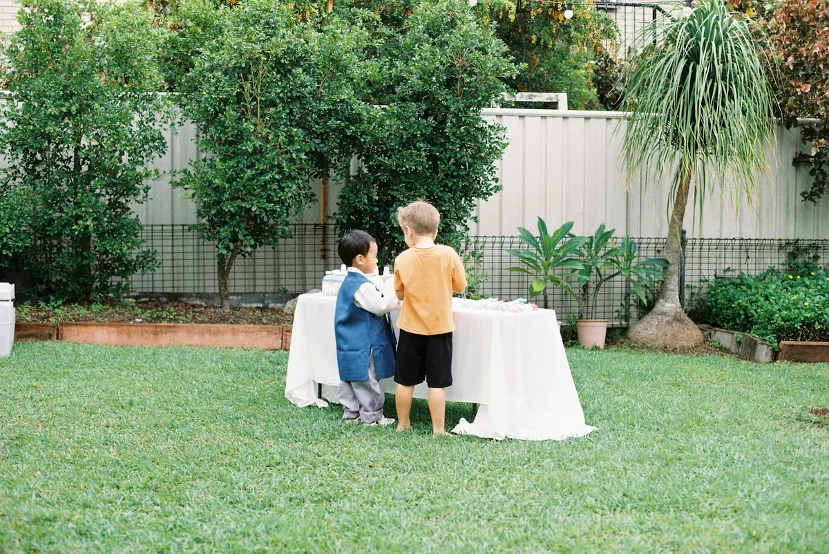 Children gathered around a small party table set up outdoors
