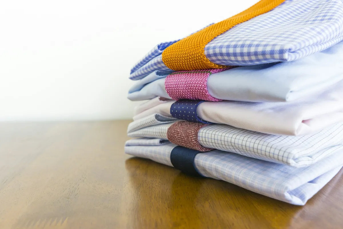 A stack of neatly folded shirts on a wooden table